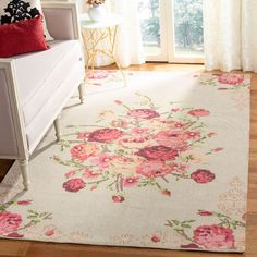 a white rug with pink flowers on it in front of a window and a couch