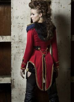 a woman in a red coat and black boots standing next to a wooden paneled wall