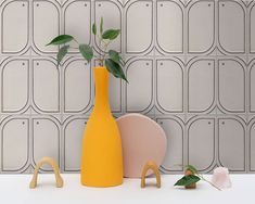 a yellow vase with a plant in it next to two pink chairs and a white wall