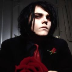 a man with long black hair holding a red rose