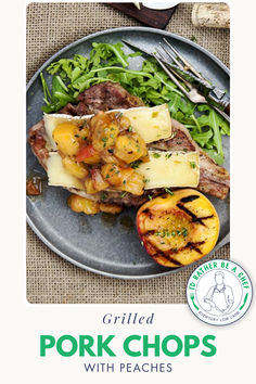 grilled pork chops with peaches on a plate next to salad and fork