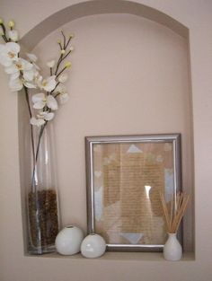 there are two vases with flowers on the shelf next to each other and an empty photo frame