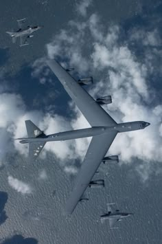 an airplane is flying in the sky with other planes around it and clouds behind it