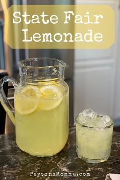 a pitcher of lemonade sitting on top of a counter next to a glass filled with ice