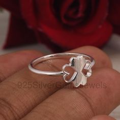 a close up of a person's hand holding a ring with a four leaf clover on it