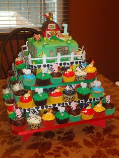 a cake with cupcakes and farm animals on it sitting on top of a table