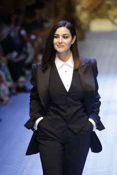 a woman walking down a runway in a suit