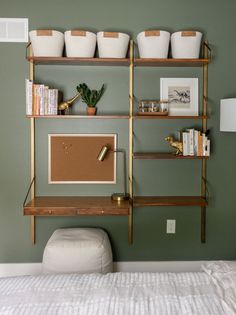 a bedroom with green walls and shelves filled with books, plants, and other items