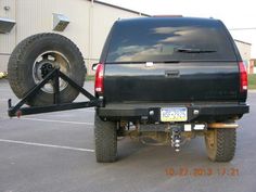 the back end of a black truck with a large tire