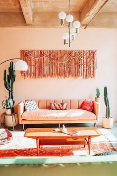 a living room with an orange couch and some cacti on the wall above it