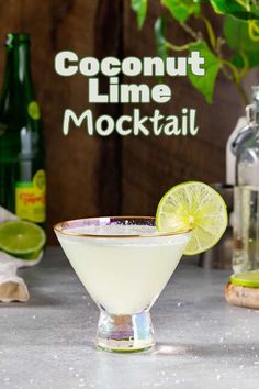 a margarita cocktail in a martini glass with a lime slice on the rim and an empty bottle behind it