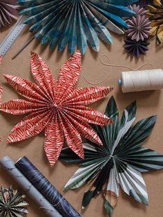 several different types of origami flowers and spools of thread on a table