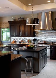 a large kitchen with an island in the middle and stainless steel appliances on the wall