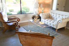 a living room with a couch, chair and coffee table in front of a window