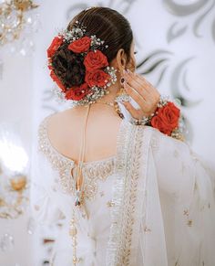 a woman with flowers in her hair wearing a white dress and holding onto the back of her head