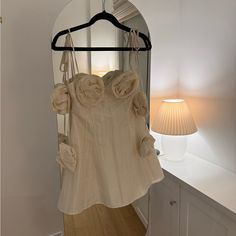 a dress hanging on a hanger in front of a mirror with a lamp next to it