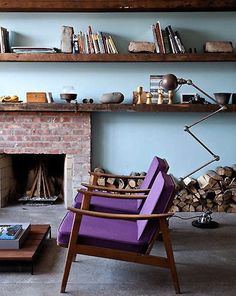 a living room filled with furniture and a fire place next to a brick wall covered in books