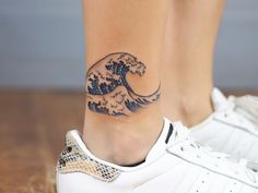 a woman's foot with a wave tattoo on the side of her left leg