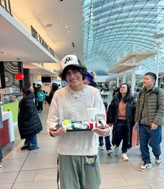 a young man holding a tray of food in a mall