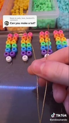 someone is trying to make bead letters out of plastic beads that are colored rainbows