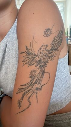 a woman's arm with a bird and flower tattoo on the left side of her arm