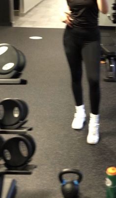 a woman is running through the gym with her headphones in her ears and other equipment behind her