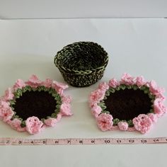 two crocheted flower pots next to a measuring tape