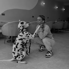 a woman kneeling down next to a dalmatian dog