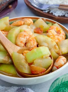 a bowl filled with shrimp and cucumber next to rice