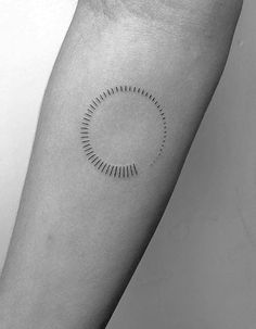 a black and white photo of a person's arm with a circle tattoo on it