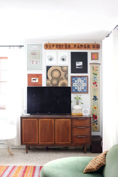 a flat screen tv sitting on top of a wooden cabinet next to a green couch