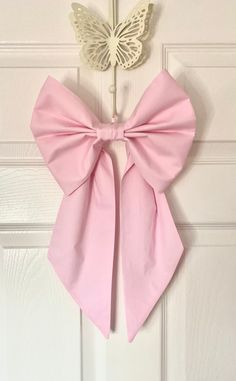 a pink bow hangs on the front door with a white butterfly hanging from it's side