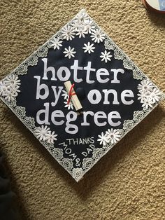 a black and white graduation cap with the words hotter by one degree on it