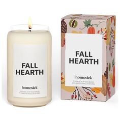 a white candle sitting next to a box on top of a wooden table with the words fall hearth printed on it