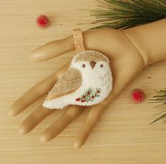 an ornament that is on top of a doll's hand with pine needles