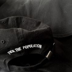 a black hat with the word park the population printed on it sitting next to a pillow