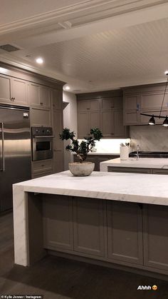 a large kitchen with stainless steel appliances and marble counter tops, along with an island in the middle