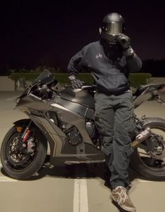 a man sitting on top of a motorcycle wearing a helmet and holding a cell phone to his ear