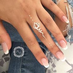 a woman's hand with white nail polish on it and a rose sticker