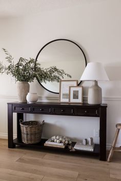 a table with two vases and a mirror on top of it next to a lamp