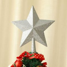 a star on top of a christmas tree with ornaments around it and ribbon wrapped around the base