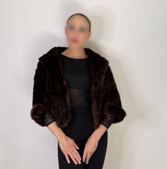 a mannequin wearing a brown fur coat and black pants with her hands on her hips