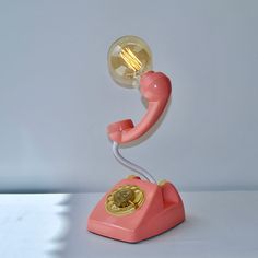 a pink telephone with a light bulb on top