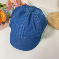 a blue hat sitting on top of a table next to flowers