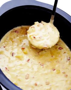 a spoon with some food in it on top of a pot filled with liquid and ice cream