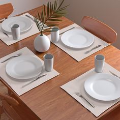 the table is set with white plates and place settings for two people to eat at