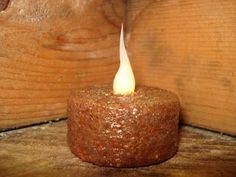 a lit candle sitting on top of a wooden table next to a piece of wood