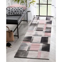 a modern rug with pink, grey and black squares on the floor in front of a window