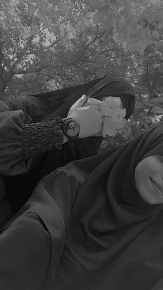 black and white photograph of a woman laying on the ground with her head covered by a blanket