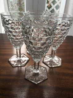 three crystal goblets sitting on top of a wooden table